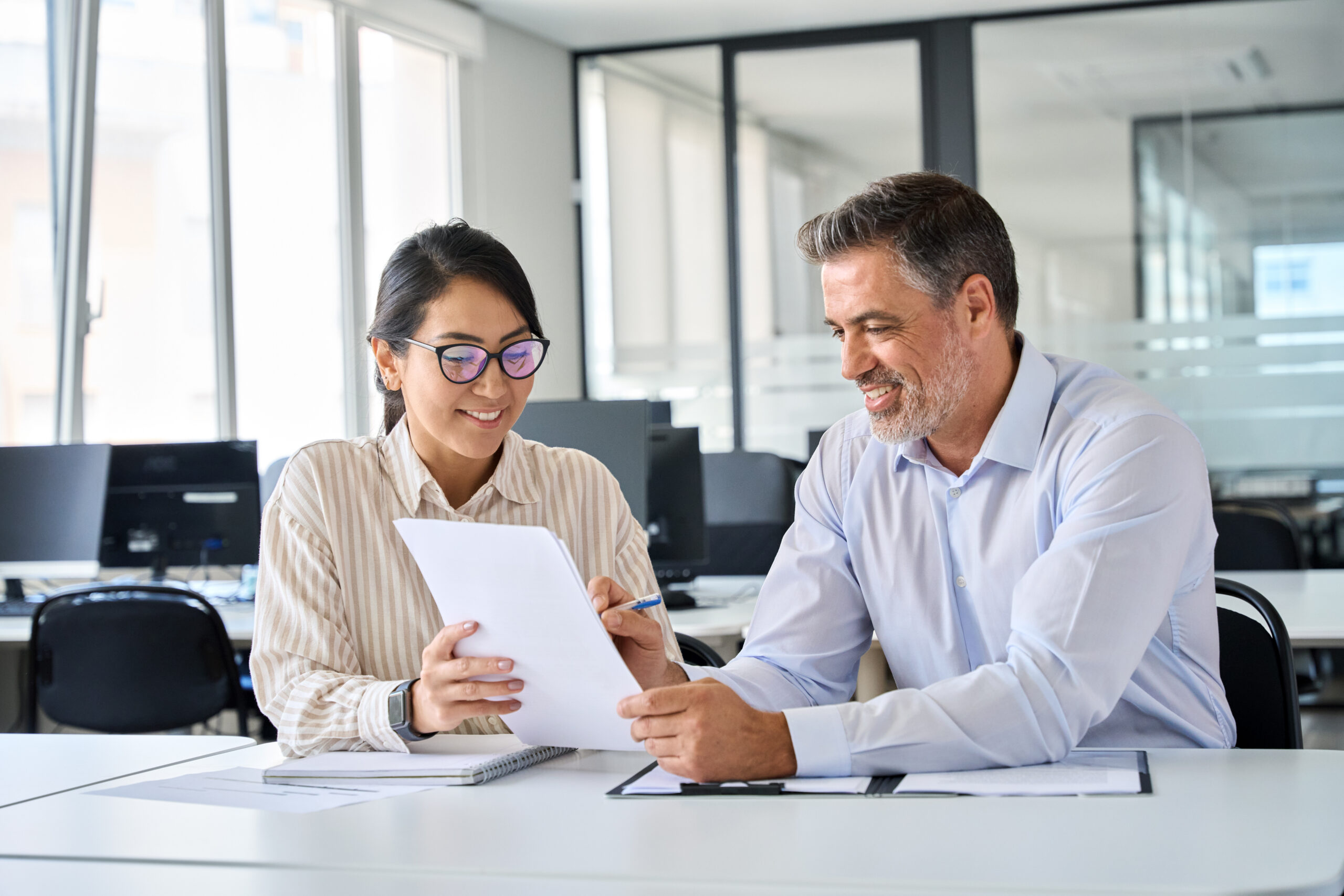 Two business professionals smile while looking at a document together.