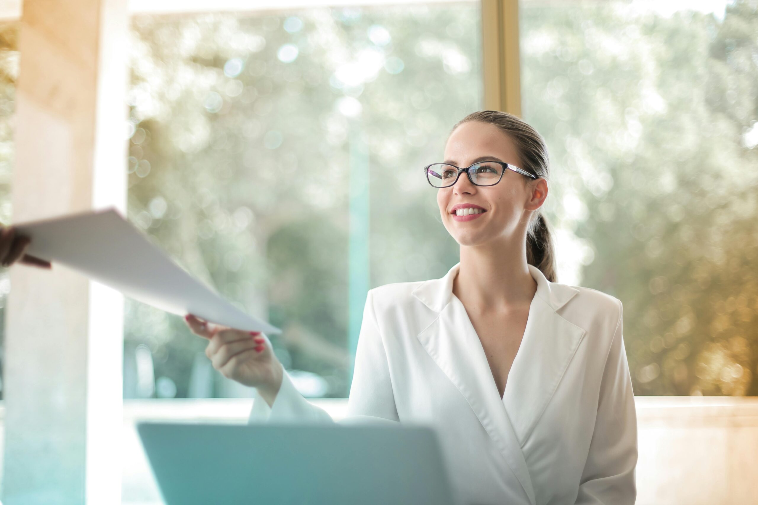 Professional woman hands a piece of paper to a person outside of the frame.